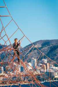 Little boy climbing on the rope at playground in Benidorm beach.
